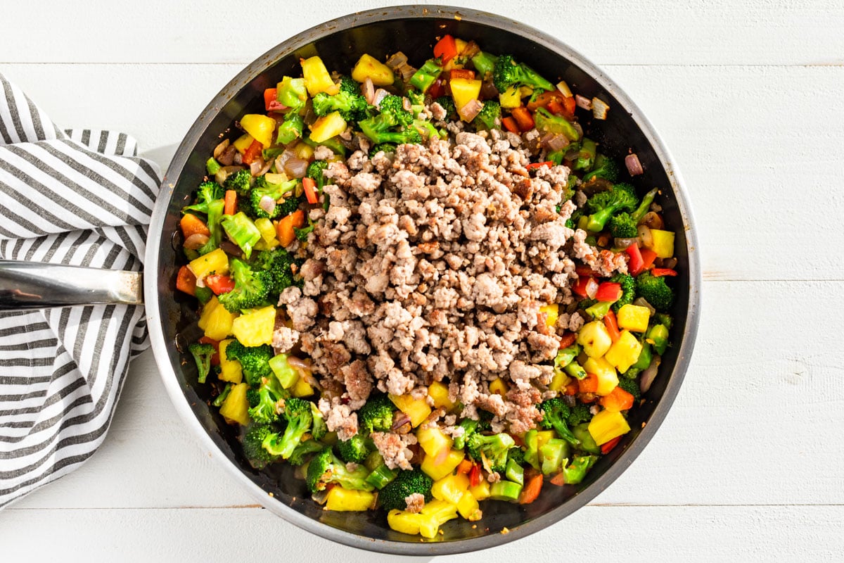 Adding the cooked ground pork to the stir fry.