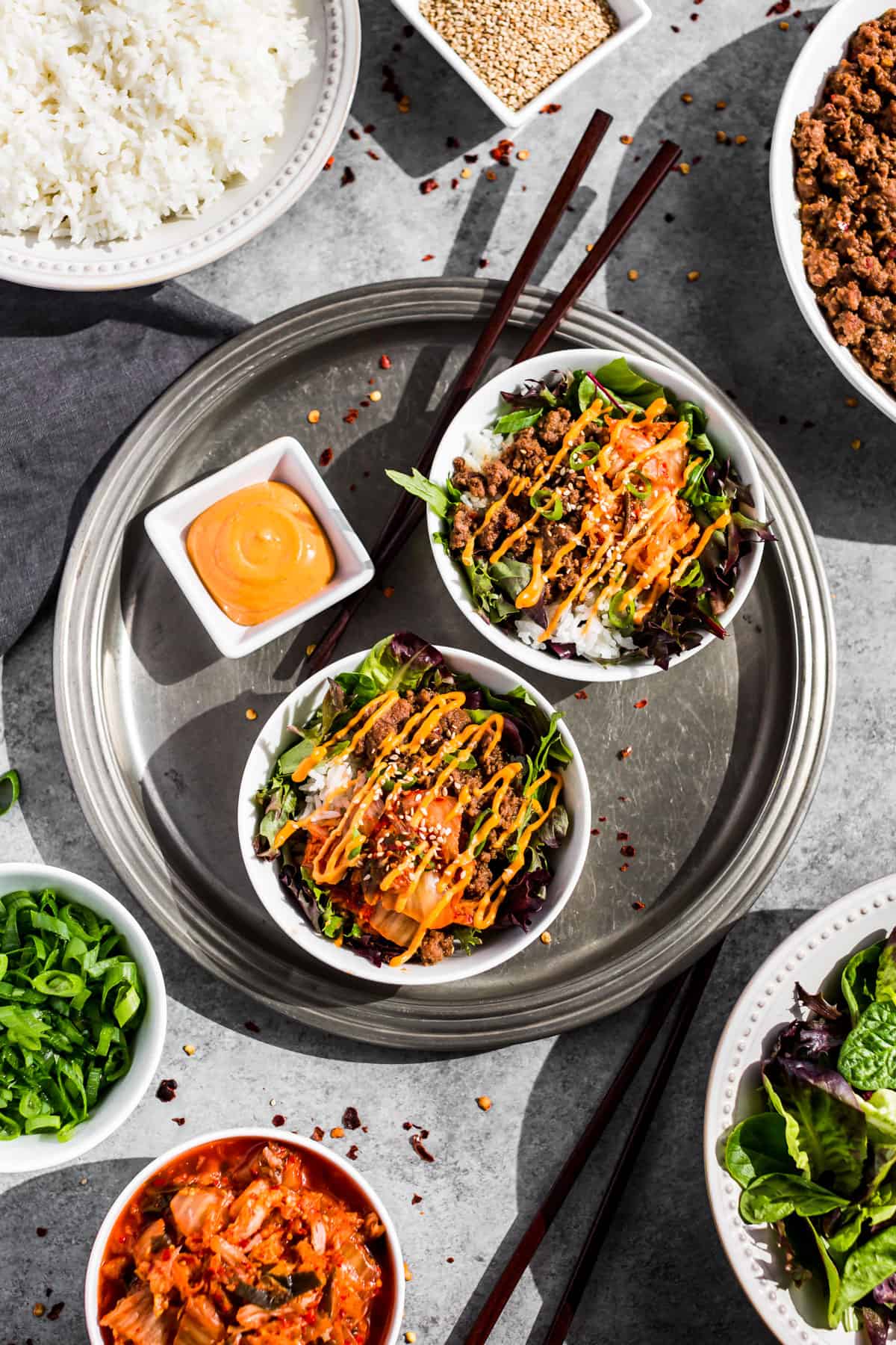 Straight down view of Korean Ground Beef Bowls on a silver tray with bowls of kimchi, rice, ground beef, and greens around it.