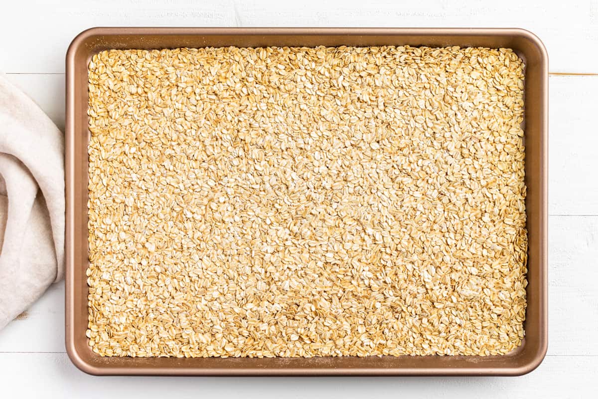 Toasting the oats on a large baking sheet.