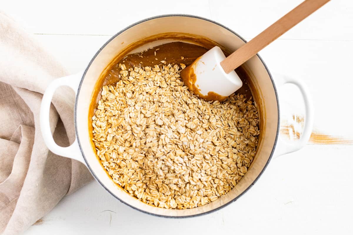 Adding the toasted oats to the peanut butter honey mixture.