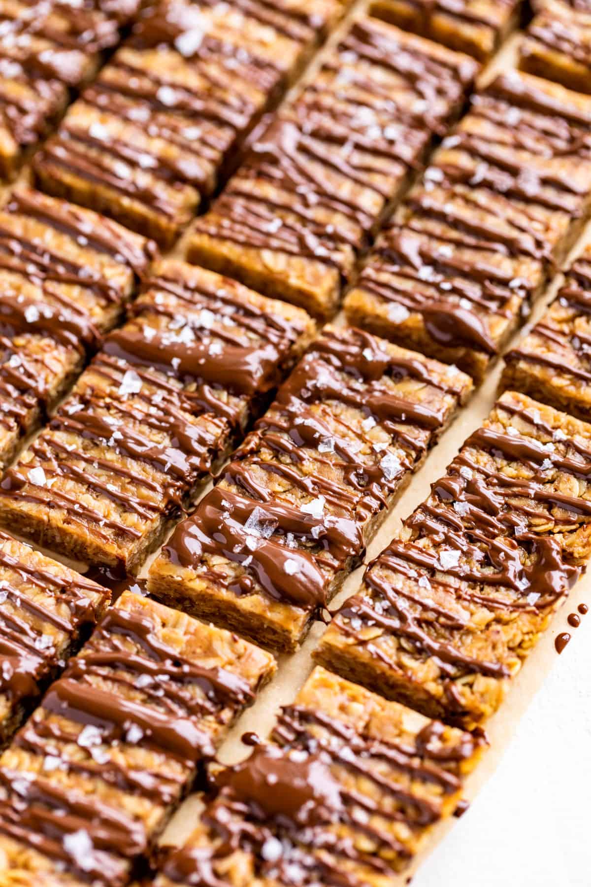 Side view of diagonal rows of Peanut Butter Granola Bars drizzled with chocolate.