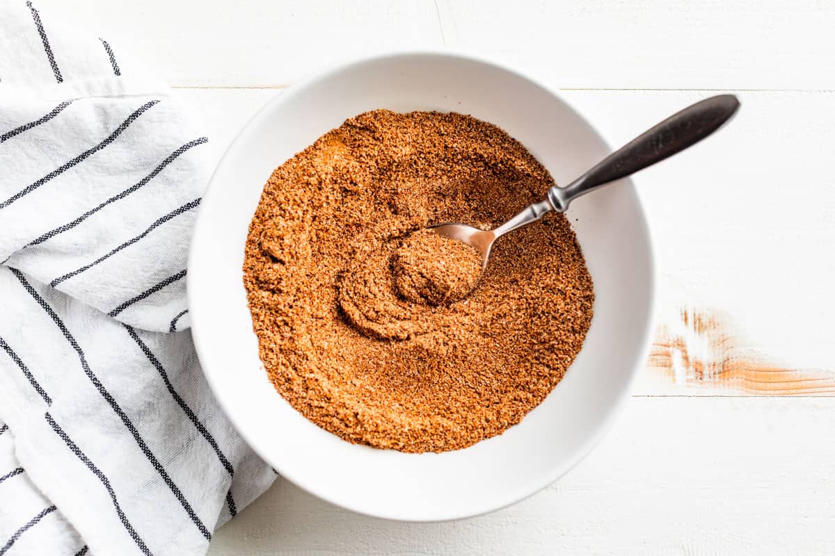 Mixing together all the spice for Taco Seasoning in a white bowl.