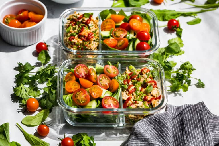 Sriracha Tuna Salad in meal prep container with arugula and cherry tomatoes.