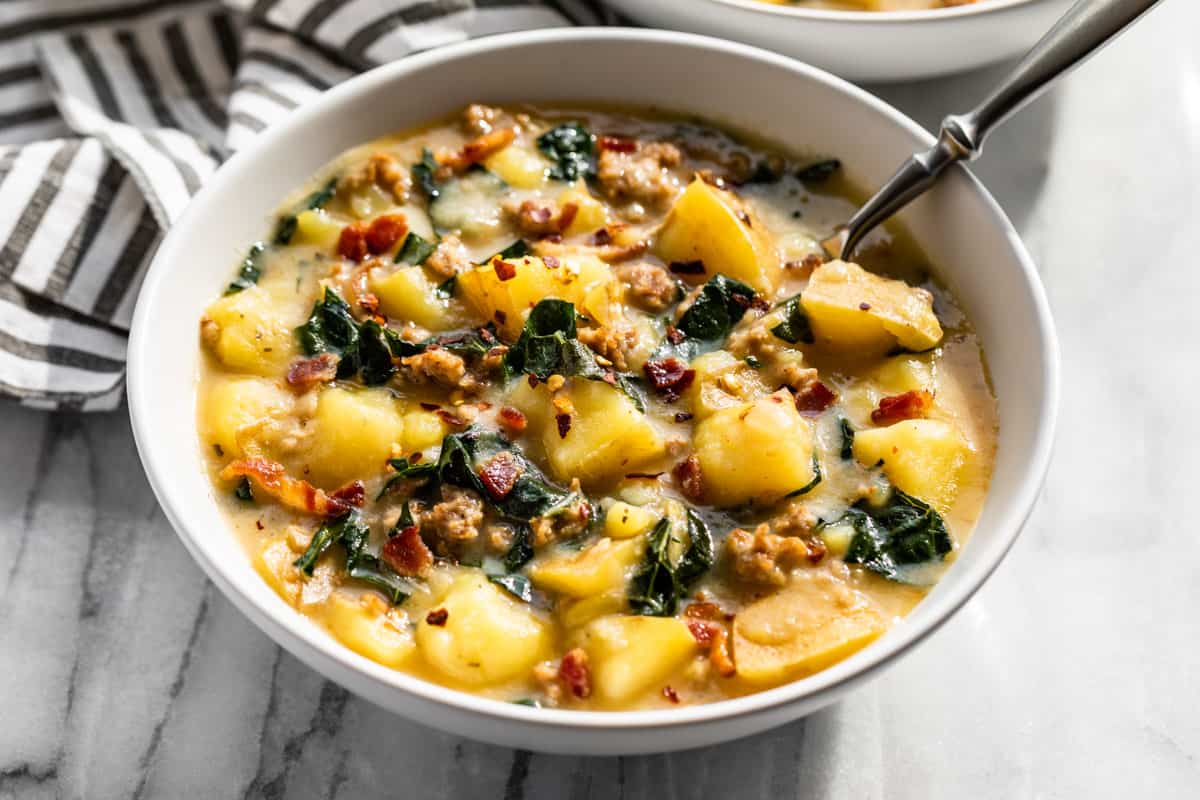 Zuppa Toscana in a white bowl with a silver spoon in it.