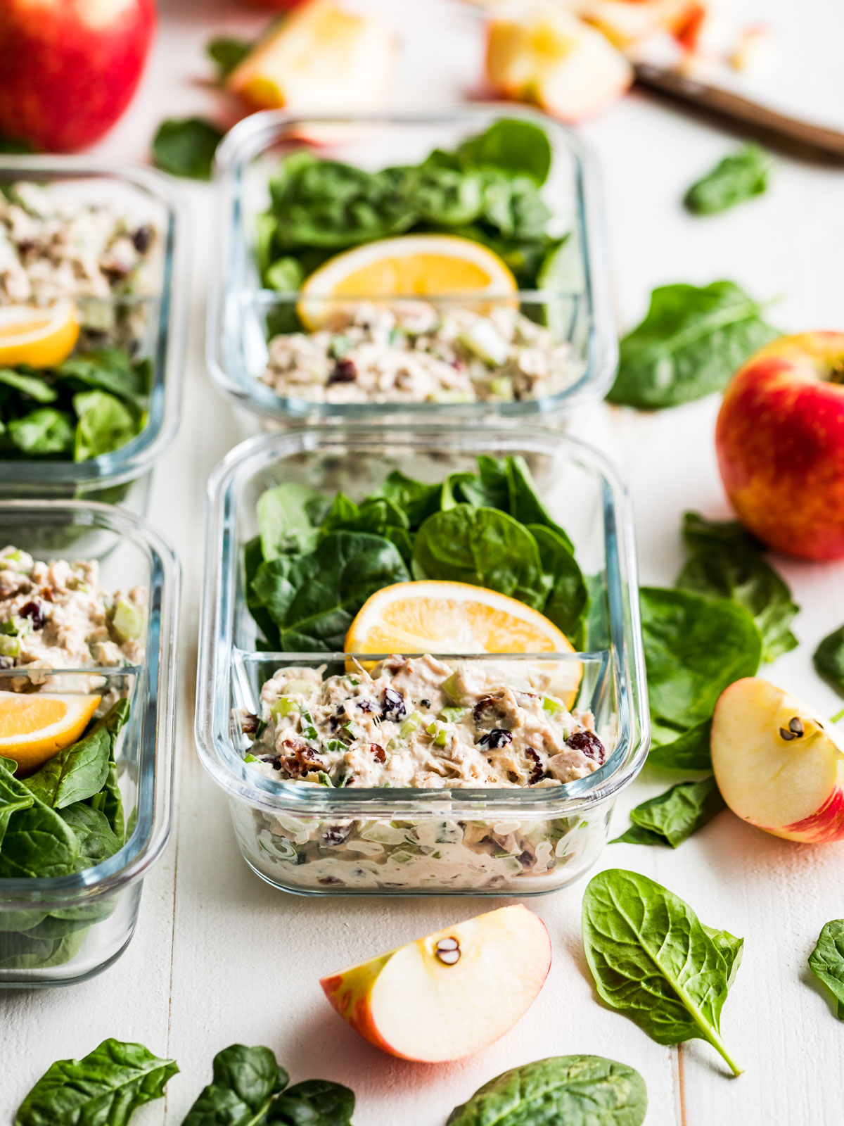 Tuna salad in meal prep containers with apples and spinach.