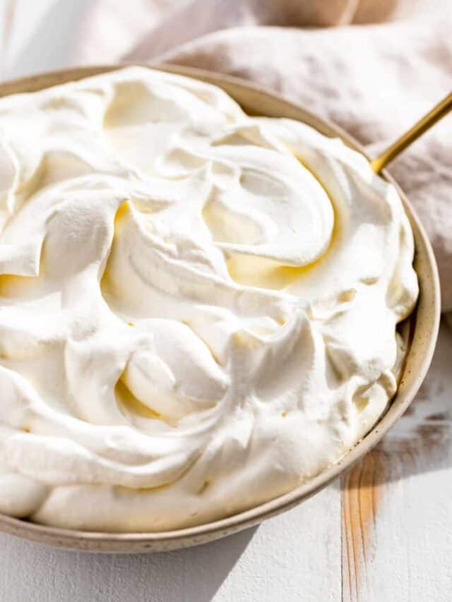 Side view of whipped cream in a pottery bowl with a gold spoon in it!