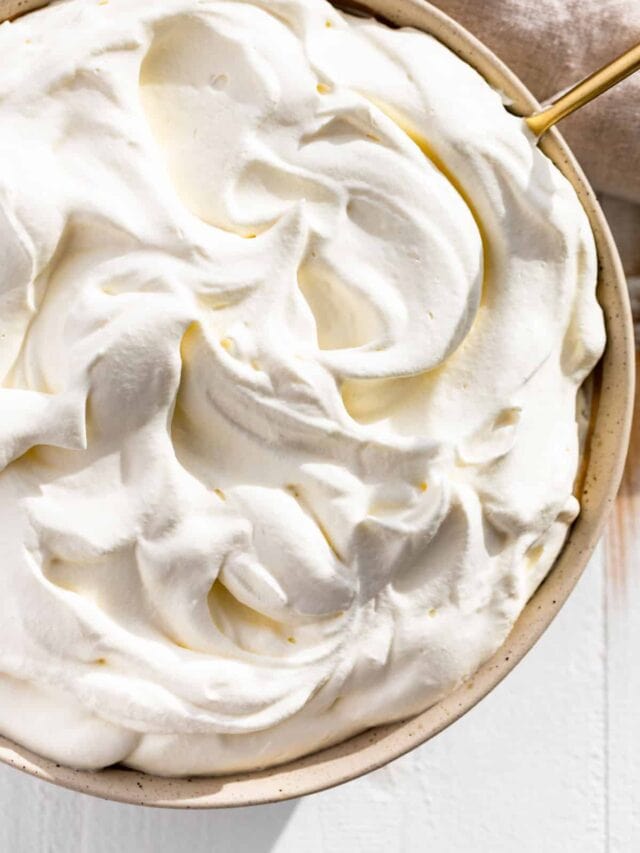 Downwards view of whipped cream in a pottery bowl with a gold spoon in it.