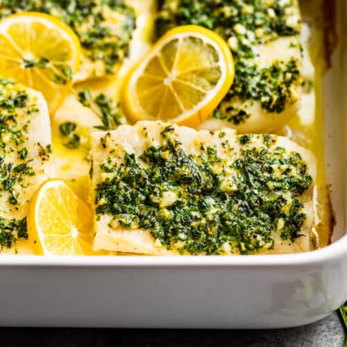 A close view of the baked lemon cod in a white baking dish.