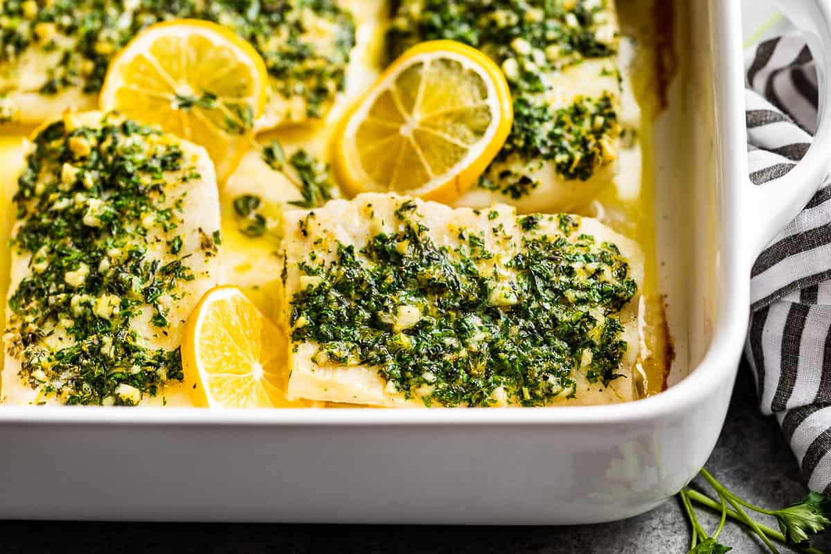 A close view of the baked lemon cod in a white baking dish.