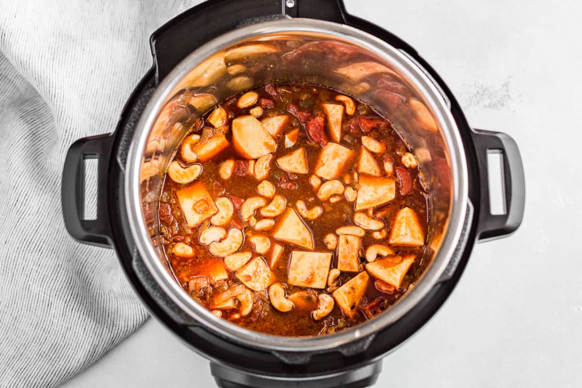 Adding the sweet potato, diced tomatoes, cashews and green chilis to the instant pot.