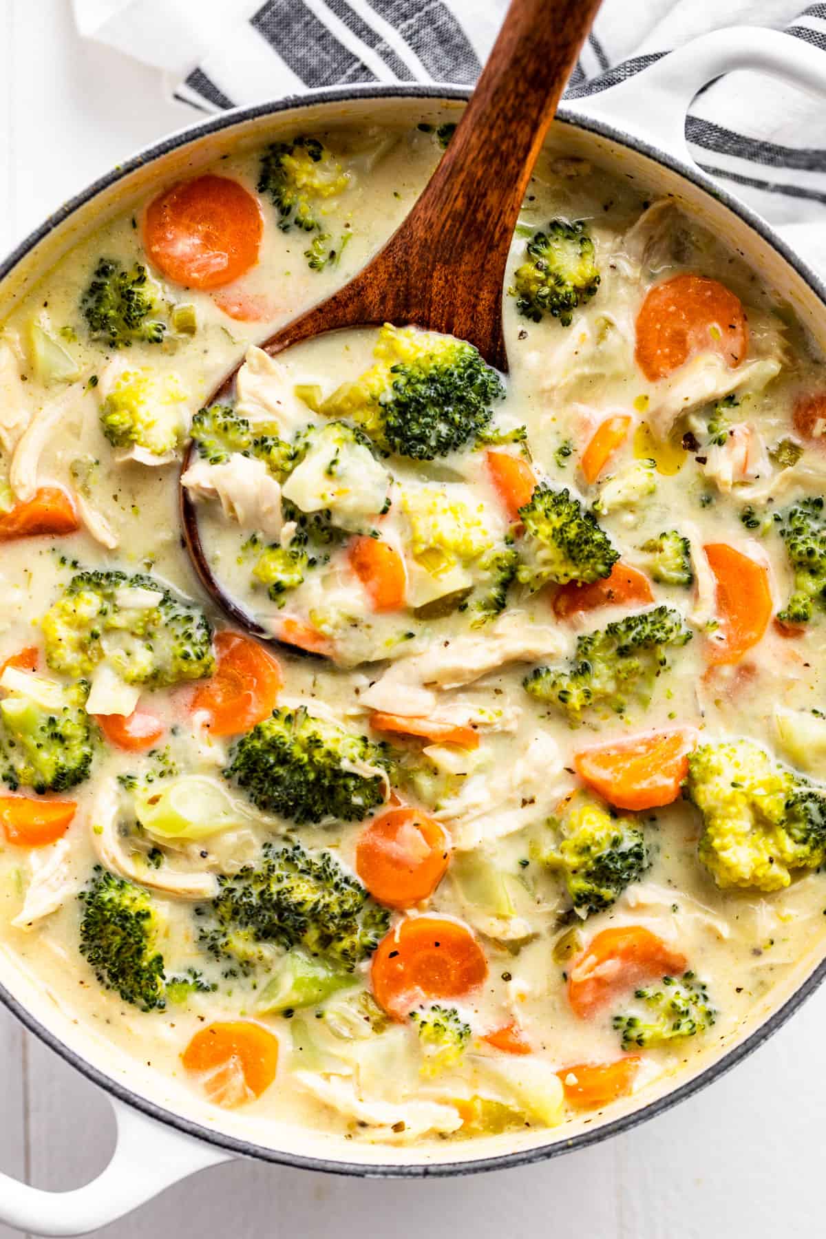 Straight down view of Chicken Broccoli Soup in a white pot with a wood ladle.