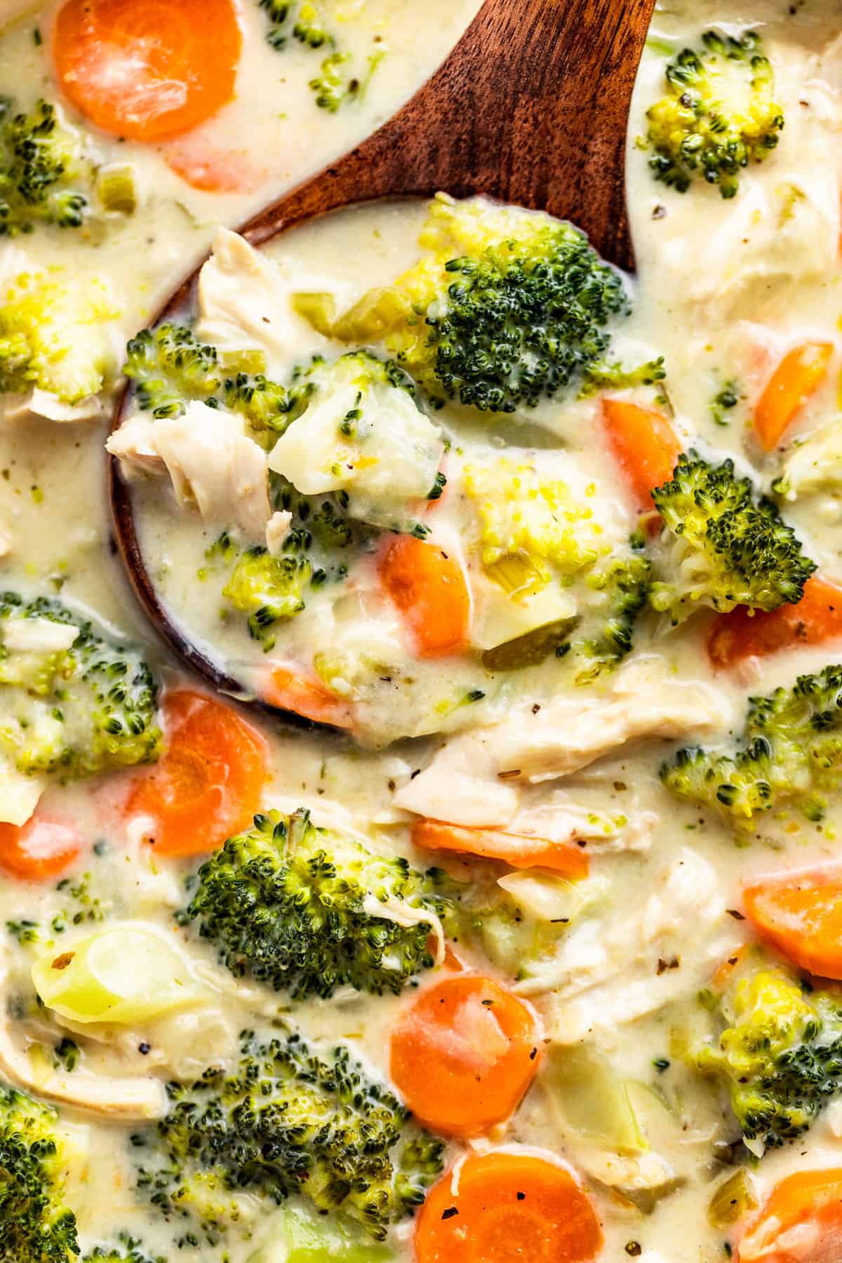 Close up macro view of Chicken Broccoli Soup being scooped out with a wood ladle.