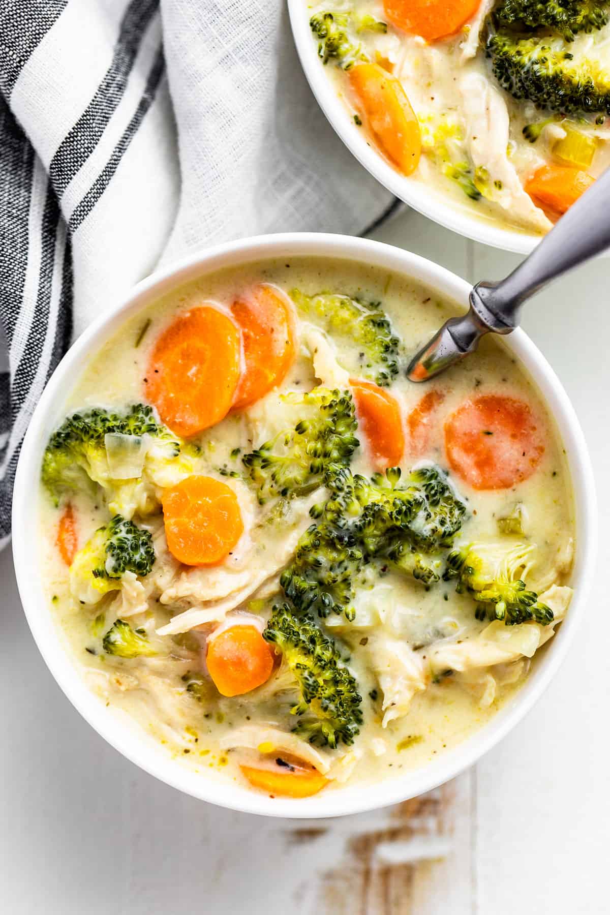 Straight down view of Chicken Broccoli Soup in two white bowls with a silver spoon.