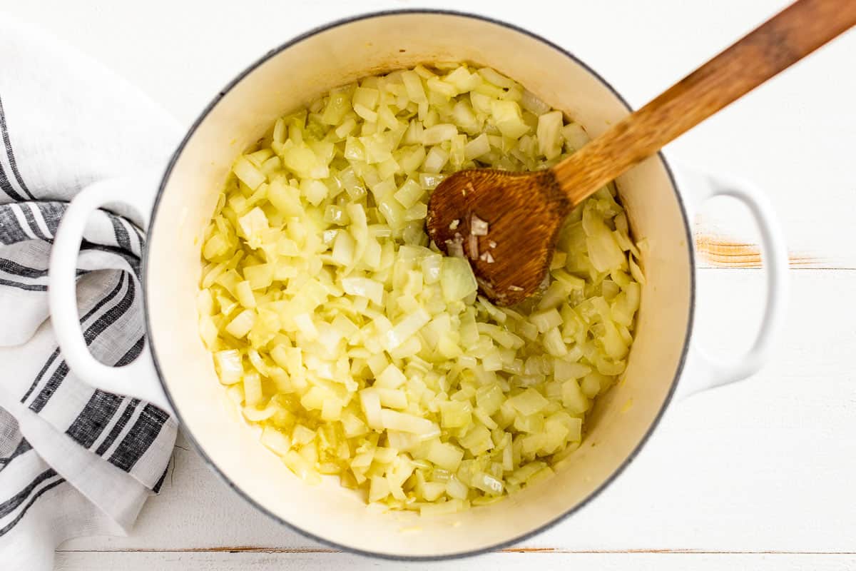 Cooking onions and garlic in a large white pot.