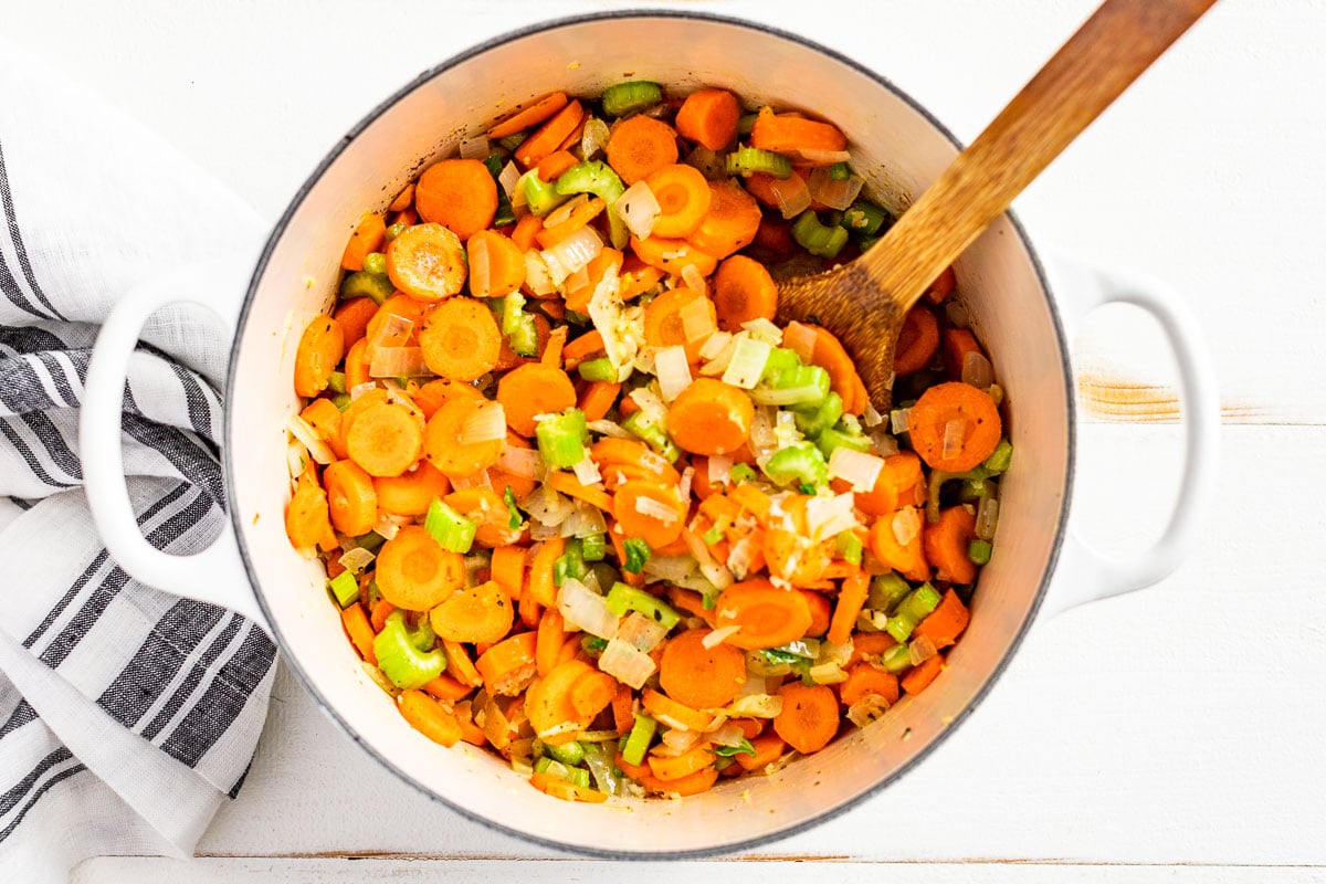 Adding the carrots and celery to the soup pot.