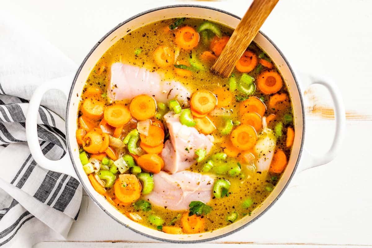 Adding the chicken stock and chicken to the soup pot.