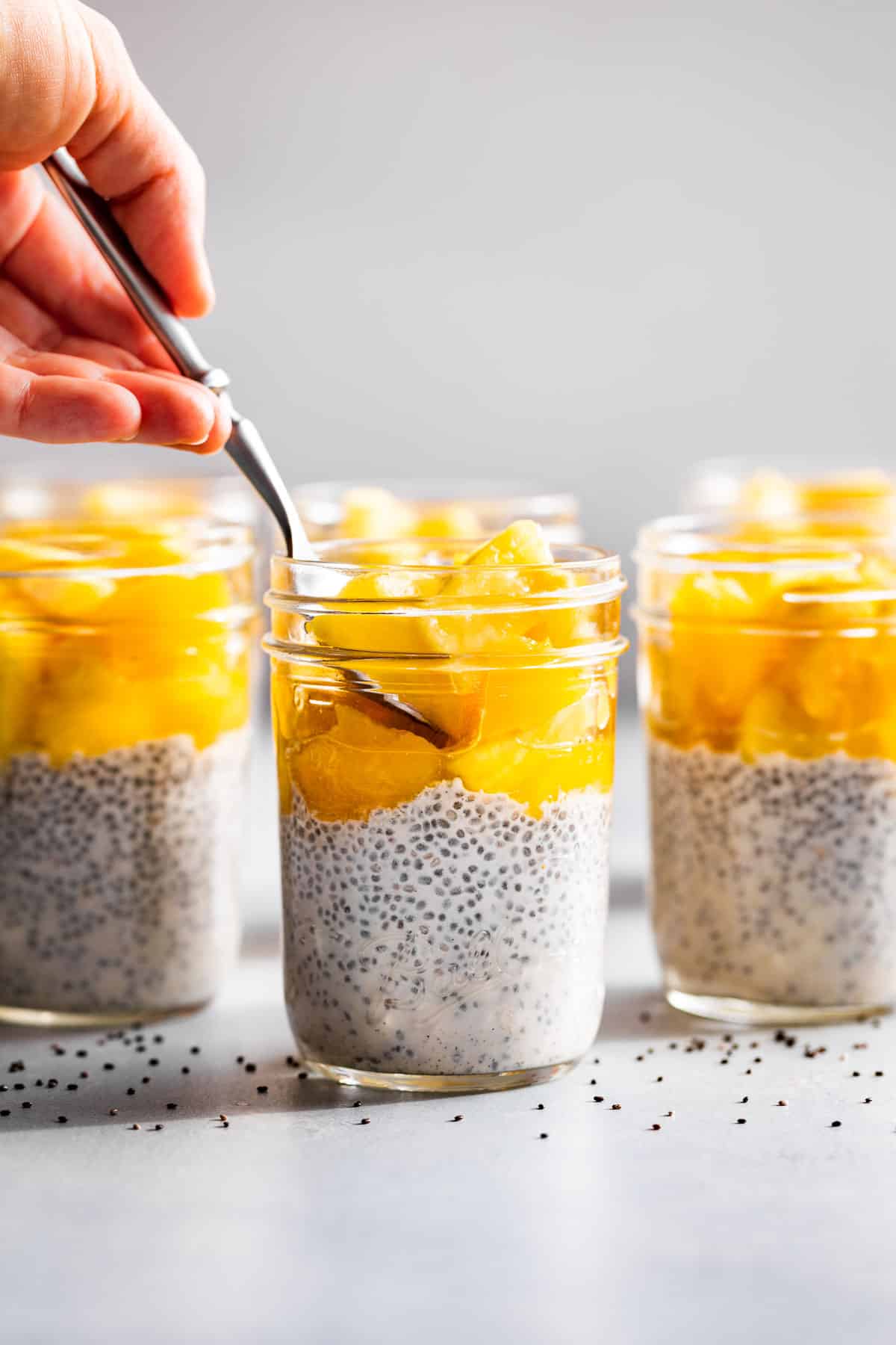 3 mason jars of creamy coconut chia pudding topped with tropical fruit.