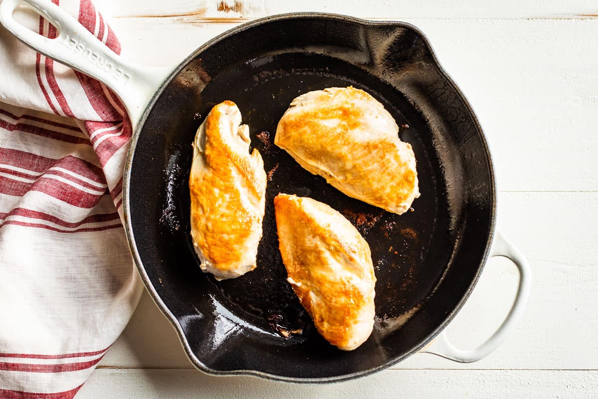 A photo of the pan seared chicken breasts as the first step in the recipe.