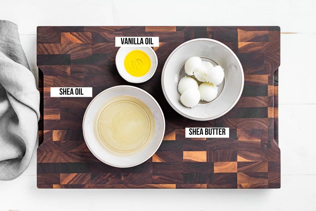 Shea oil, shea butter, and vanilla jojoba oil in small dishes on a wood cutting board.