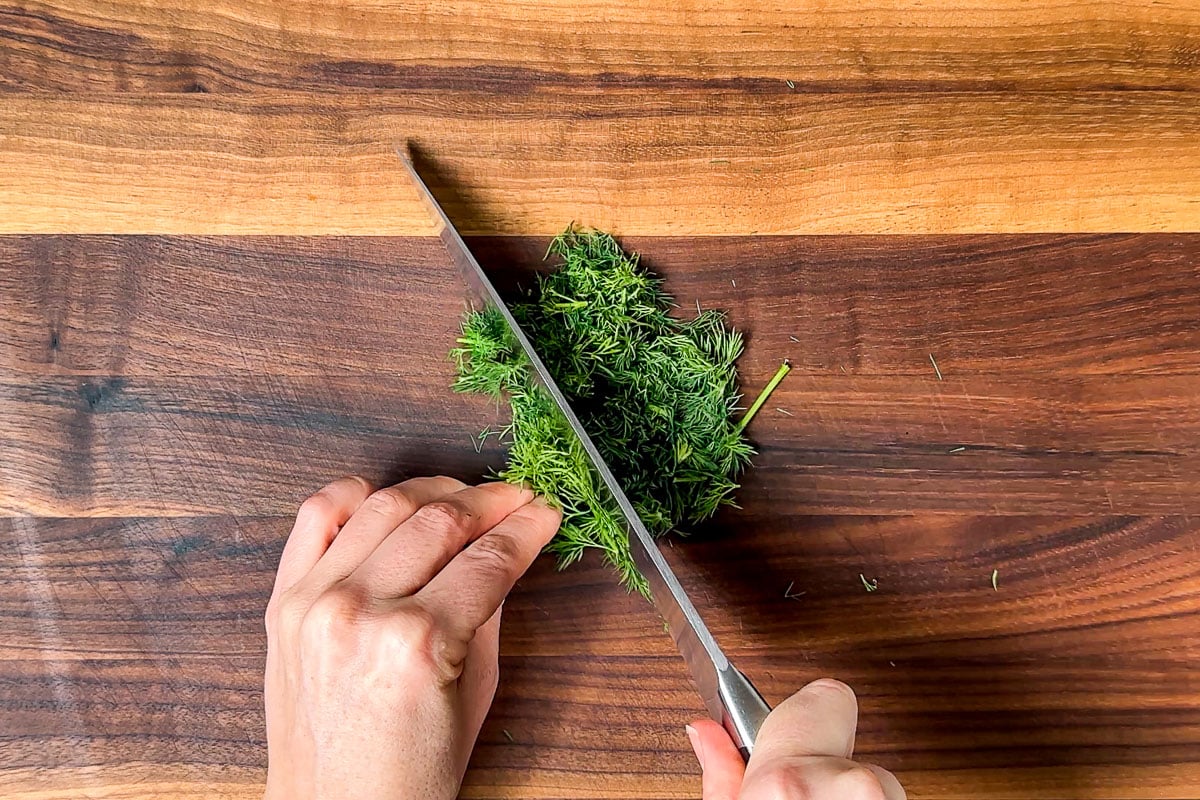 Chopping the fresh dill on a wood cutting board.