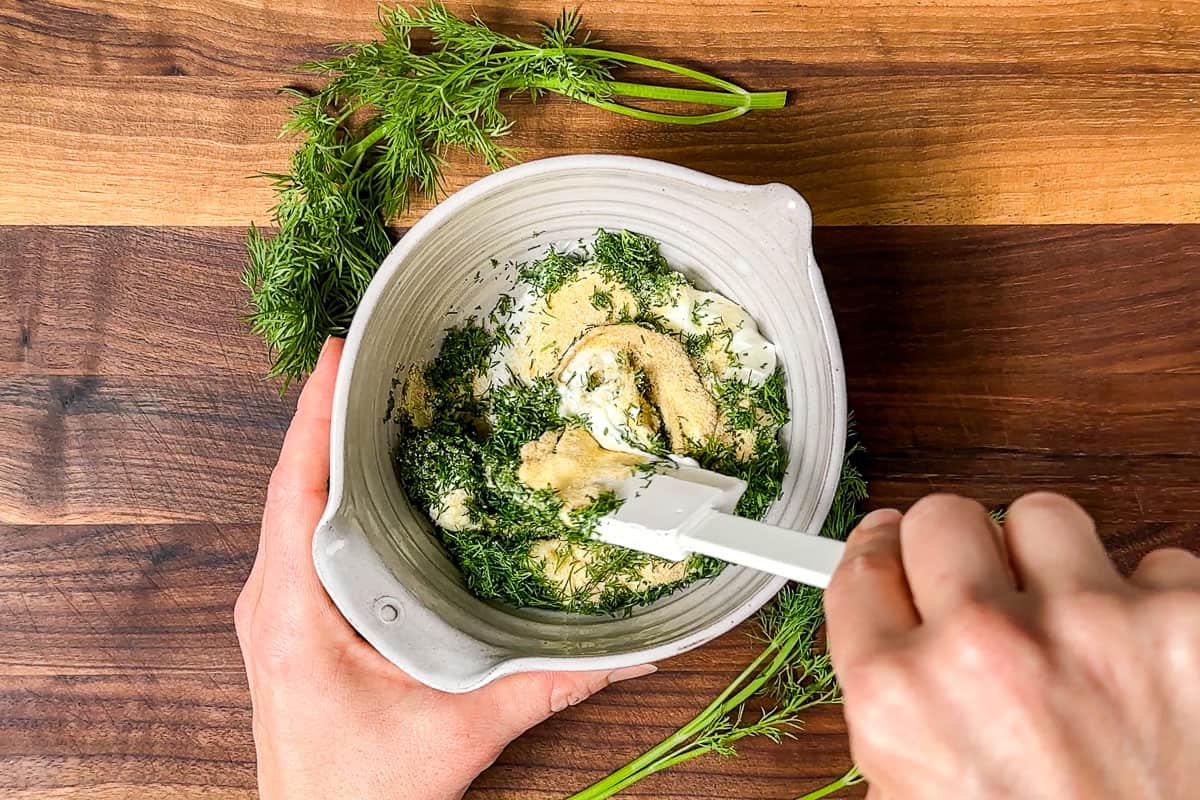 Mixing the Greek yogurt together with the garlic granules and chopped dill in a small pottery bowl.