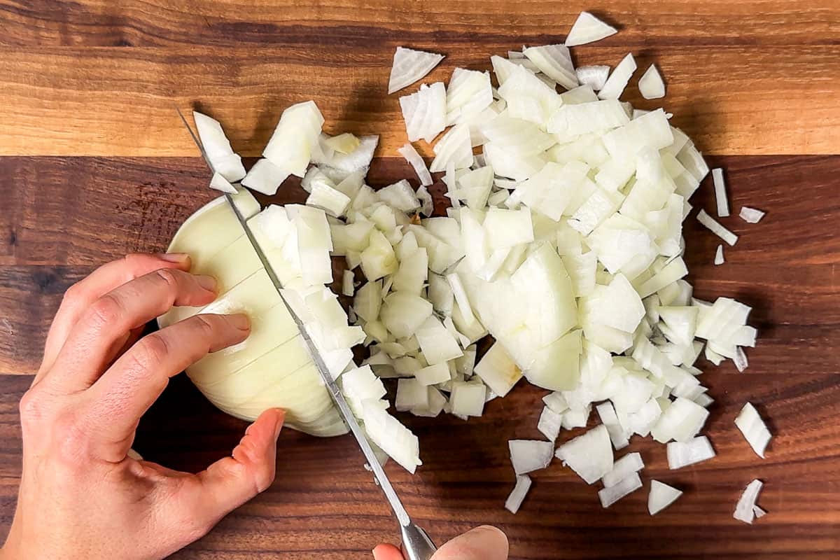 Dicing up an onion on a wood cutting board.