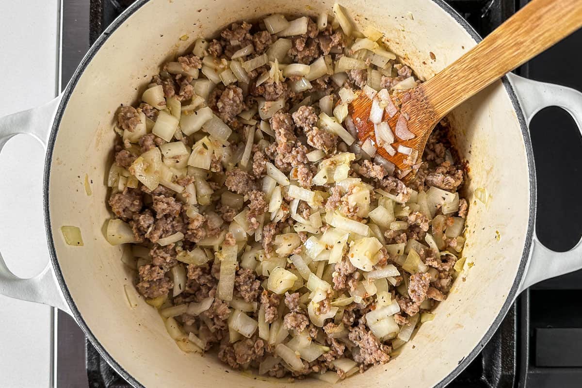 Adding the onion, garlic, and Italian seasoning to the cooked Italian sausage.