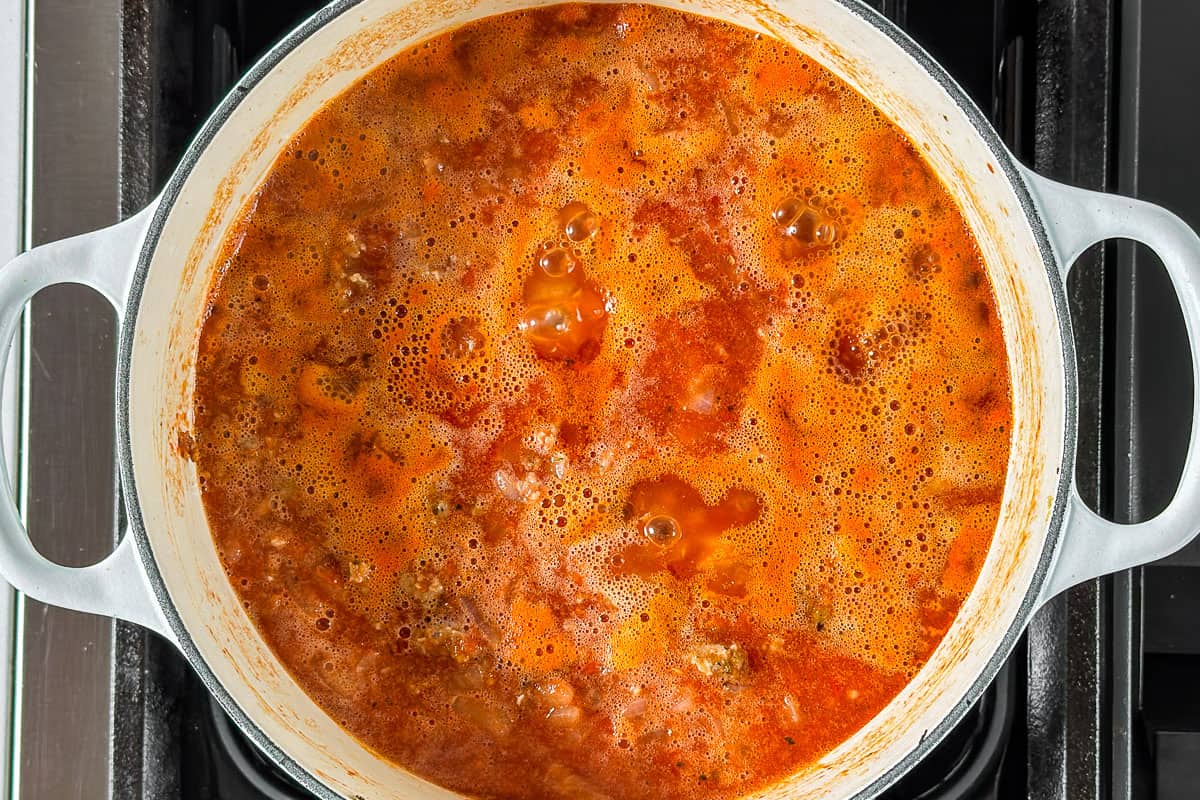 Simmering Homemade Spaghetti Sauce in a large white pot on the stove top.