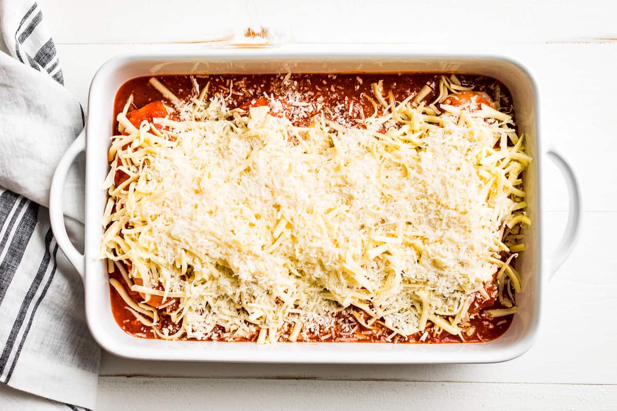 Topping the pizza chicken with grated mozzarella and grated parmesan cheese.
