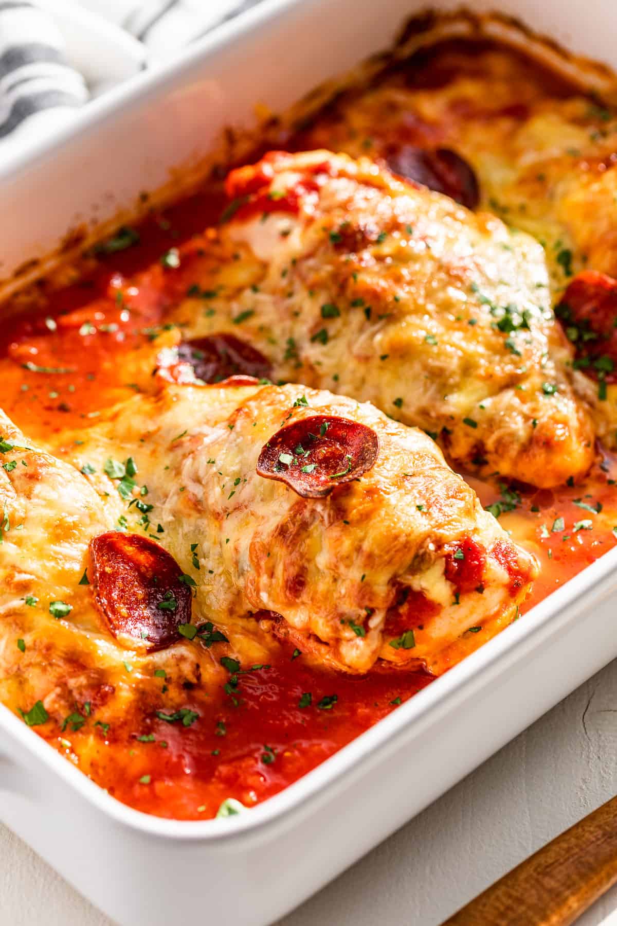 Side view of Pizza Chicken in a white baking dish.