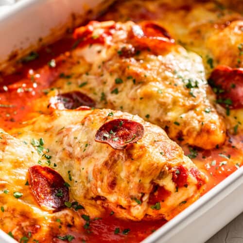 Side view of finished Pizza Chicken in a white baking dish.