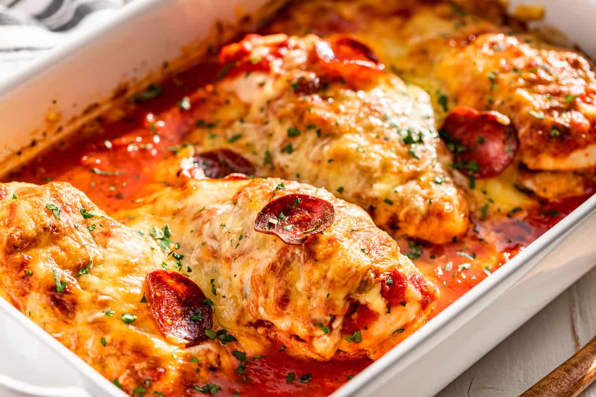 Side view of finished Pizza Chicken in a white baking dish.