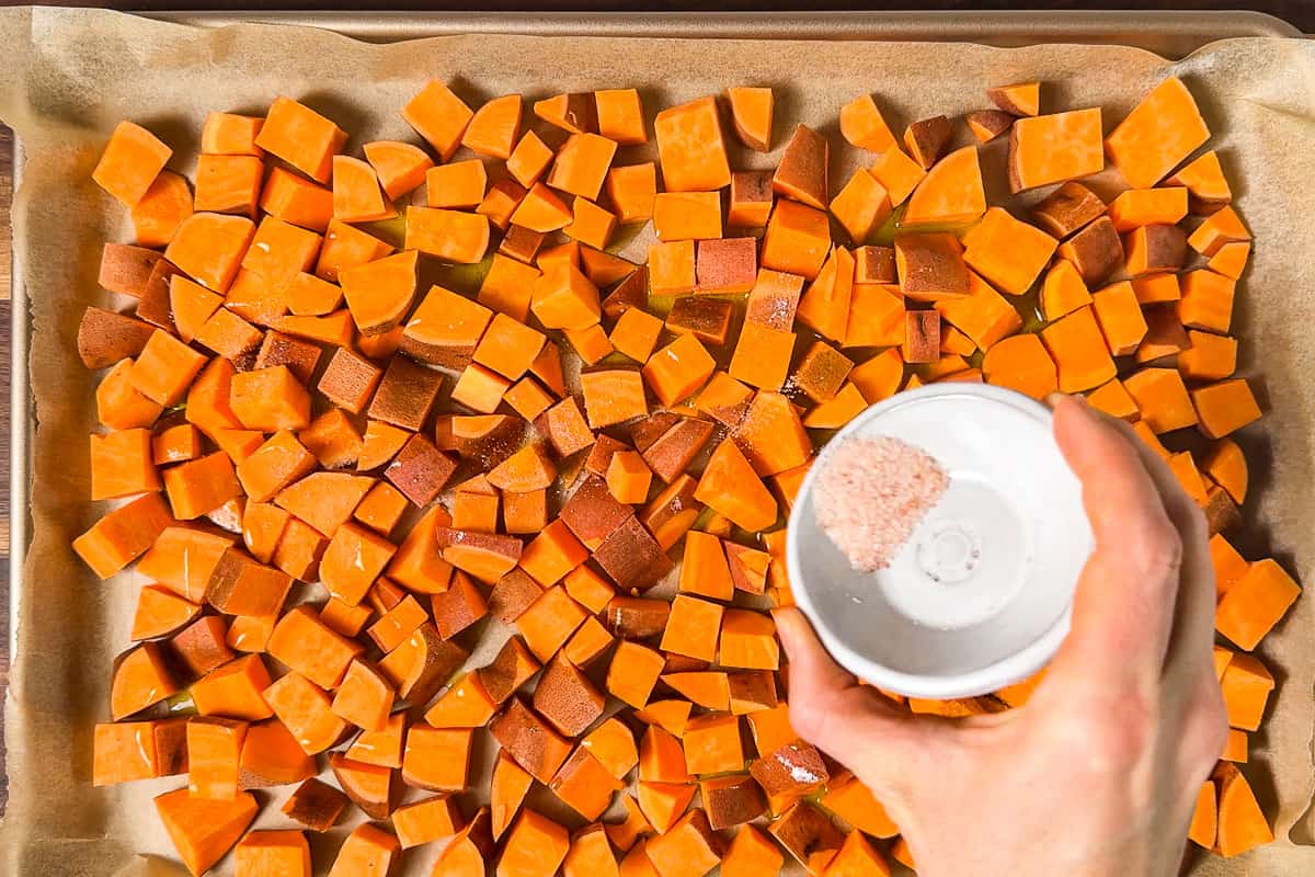 Sprinkling sea salt over the cubed sweet potatoes.