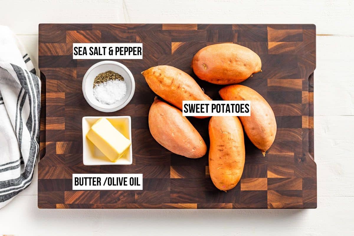 Sweet potatoes, butter, sea salt, and pepper on a wood cutting board.