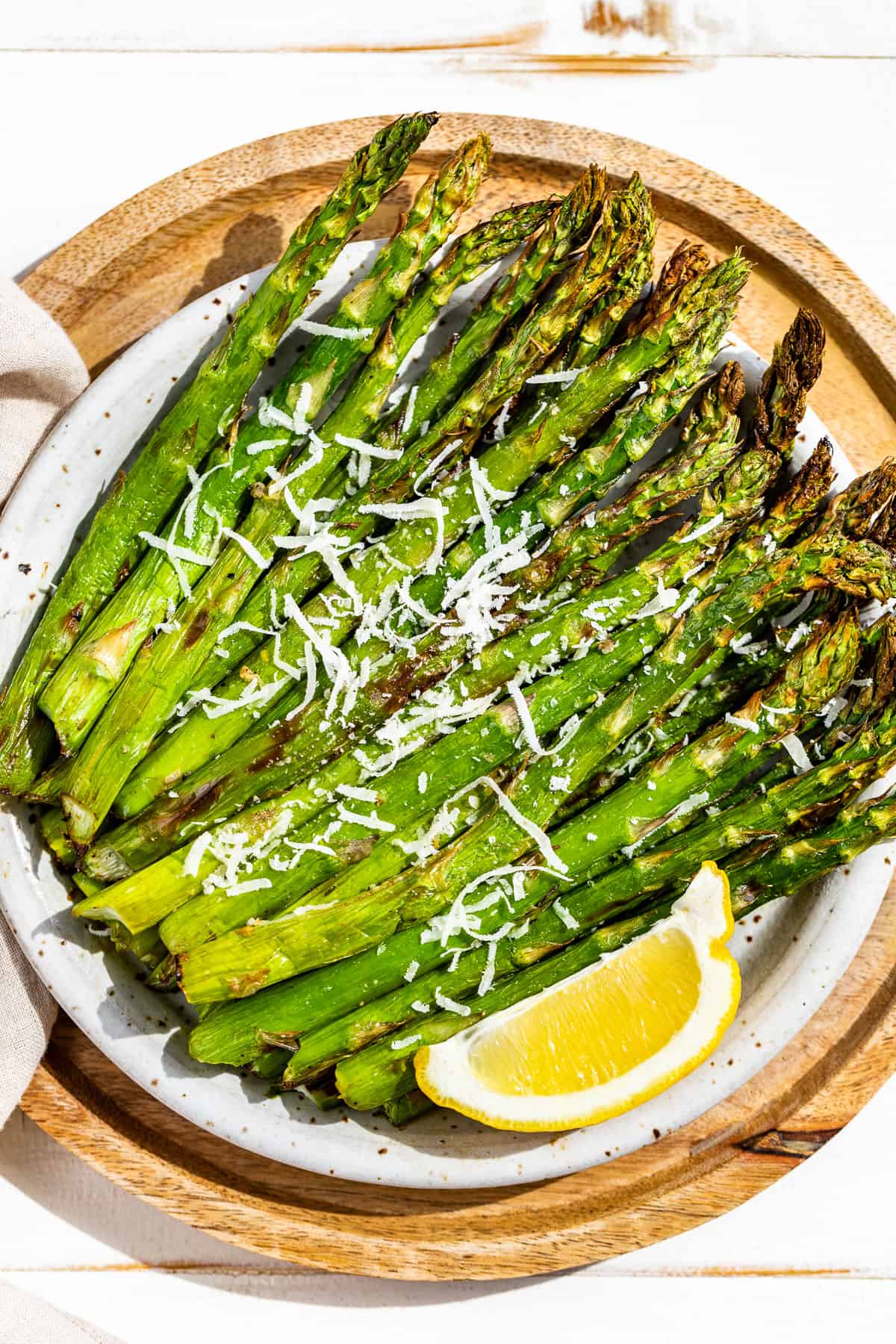 Straight down view of air fryer asparagus on a pottery plate with a linen napkin on the side.