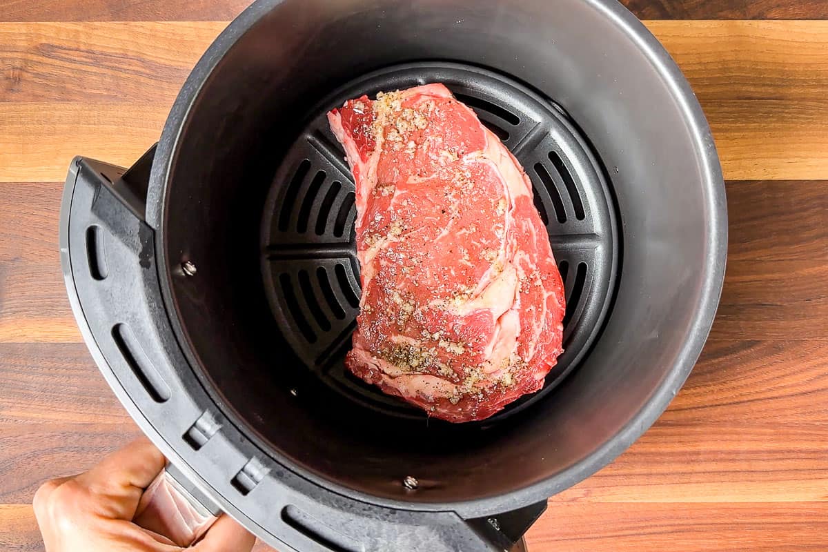 Adding the ribeye steak to the air fryer.