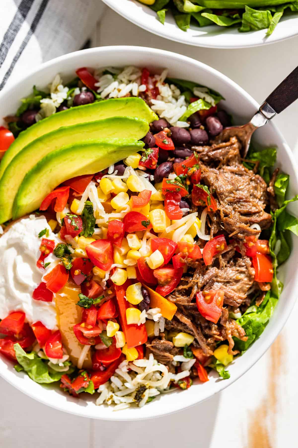 Straight down view of a Barbacoa Burrito Bowl topped with fresh Pico de Gallo and sliced avocado.