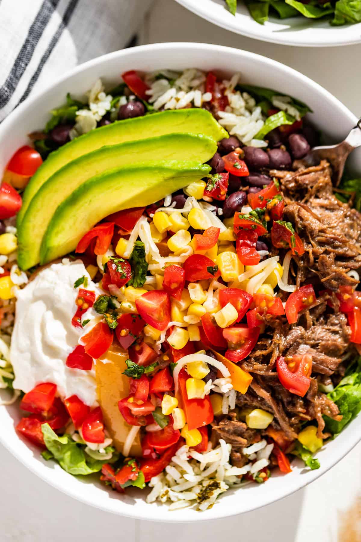 Close view of Barbacoa Burrito Bowls topped with sliced avocado.