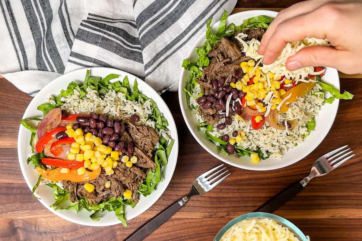 Adding the final toppings to the barbacoa burrito bowls, corn, cheese, and sour cream.