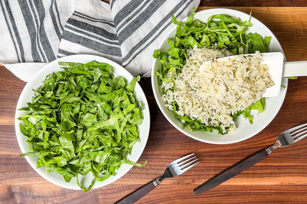 Adding shredded lettuce and Cilantro Lime Rice to two white bowls on a wood cutting board.
