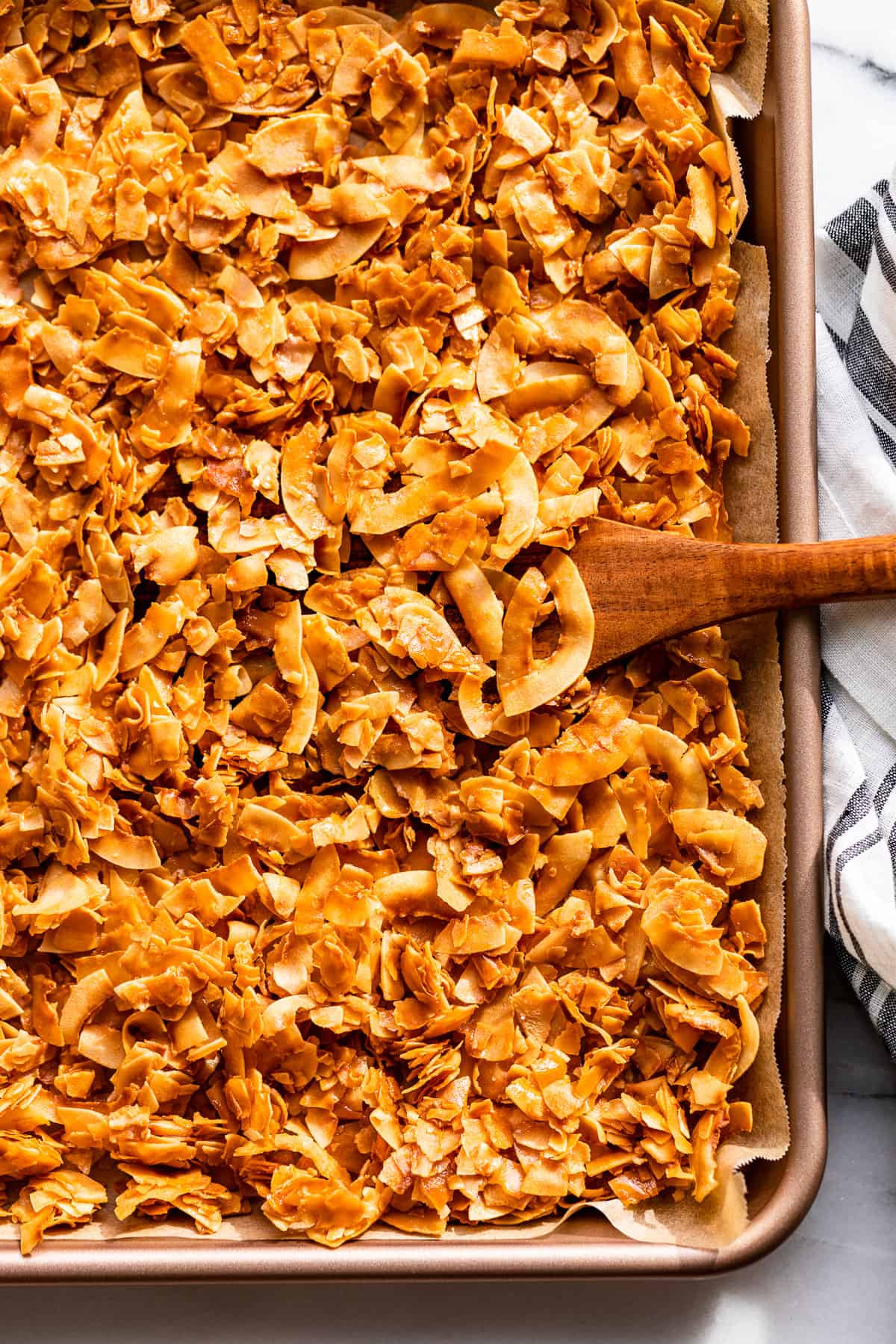 Coconut Chips on a cookie sheet with a spatula cooking some out.