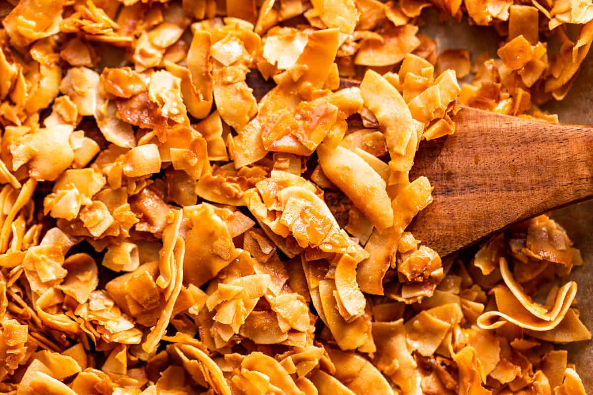 Finished Coconut Chips with a wood spatula scooping some out.