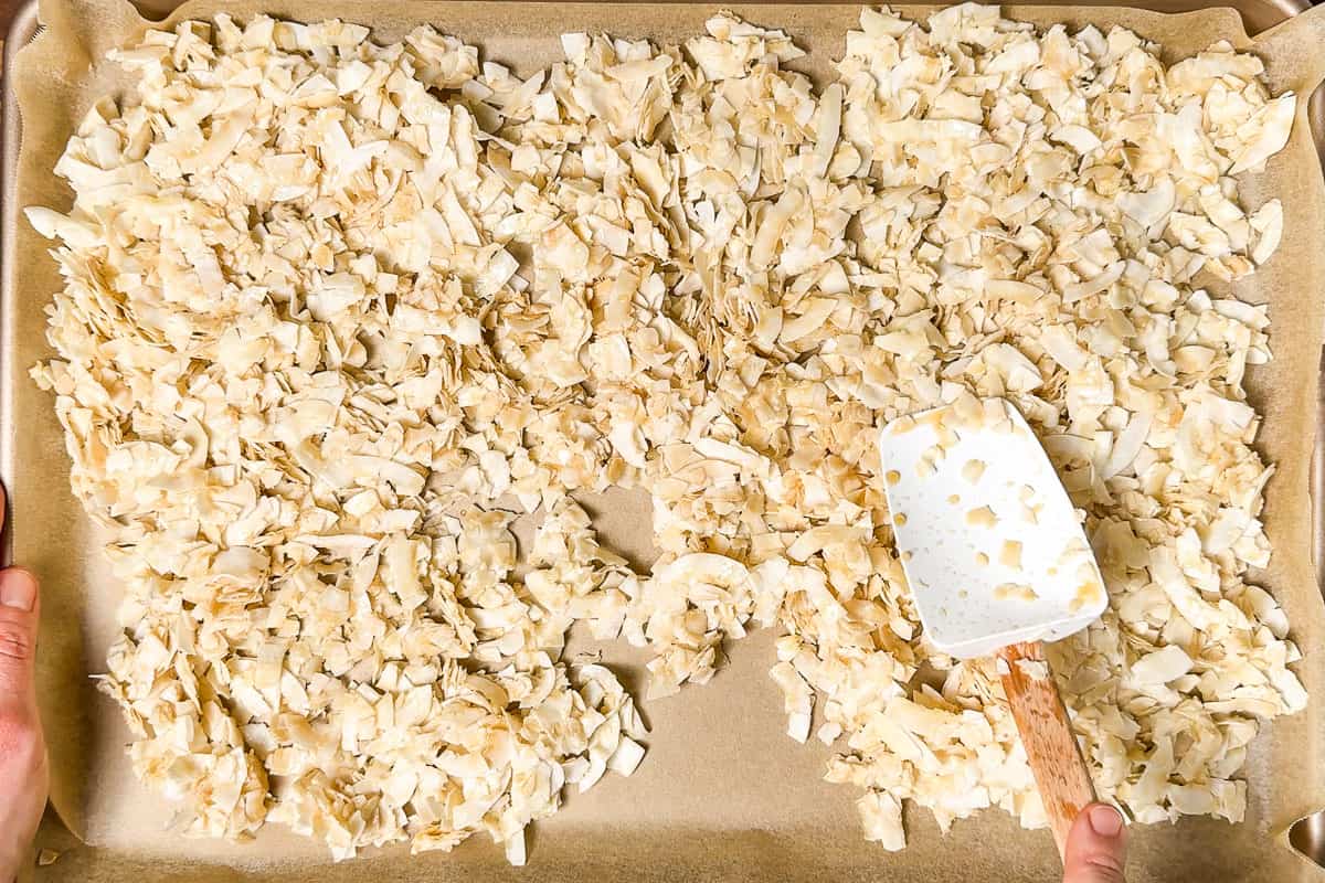 Spreading out the coconut flakes on a parchment lined baking sheet.