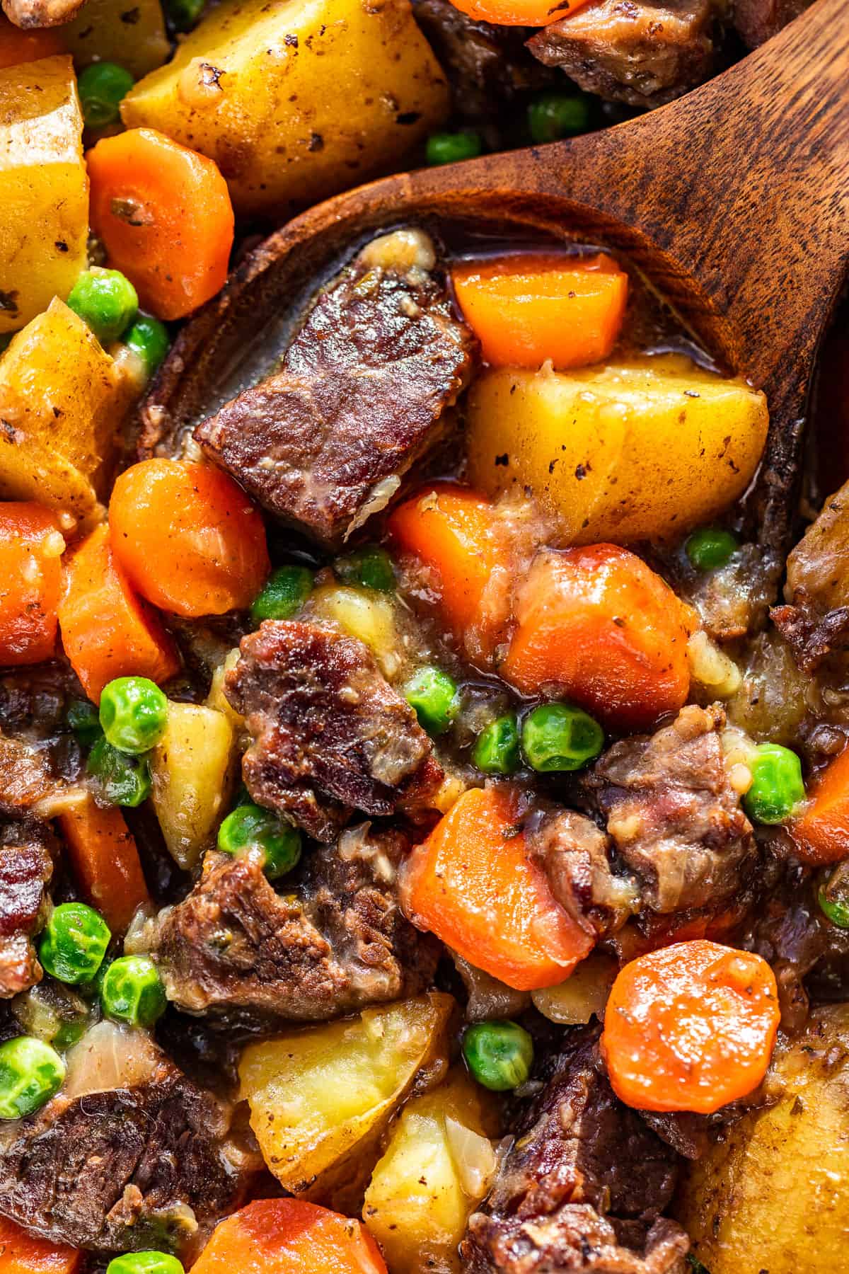 Close macro view of Dutch Oven Beef Stew with a wood ladle in it.