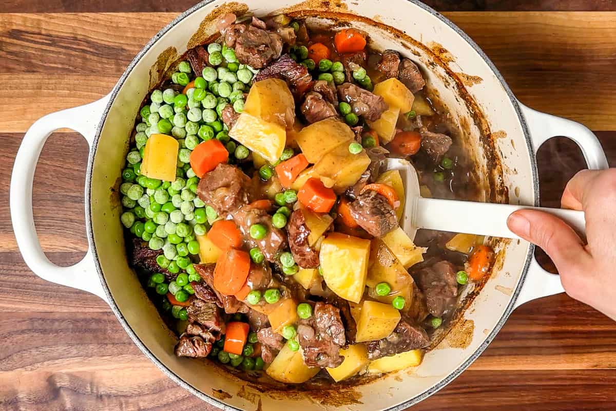 Mixing in the peas to the finished stew.