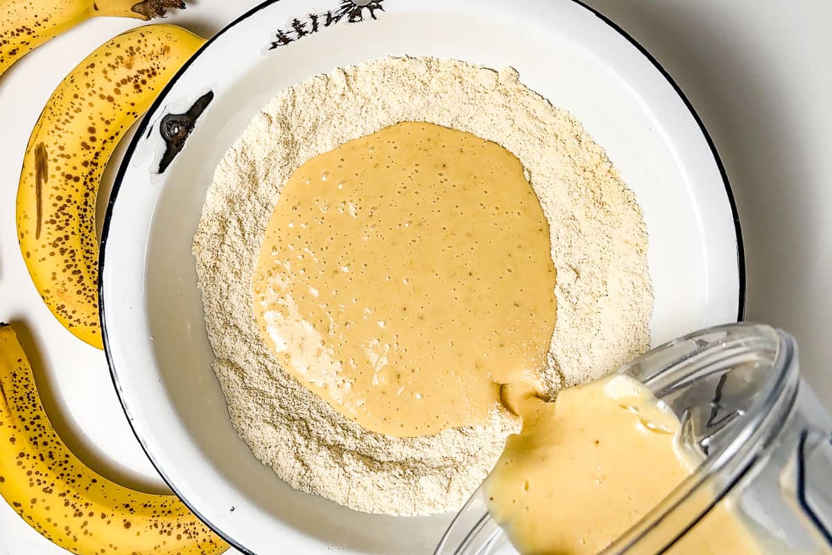 Adding the wet banana cake ingredients to the dry flour ingredients.