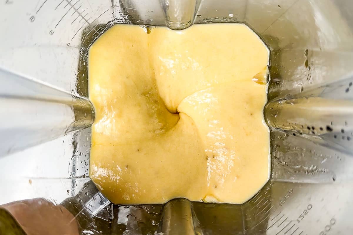 Blending the ripe bananas with eggs, maple syrup, and vanilla in a blender container.