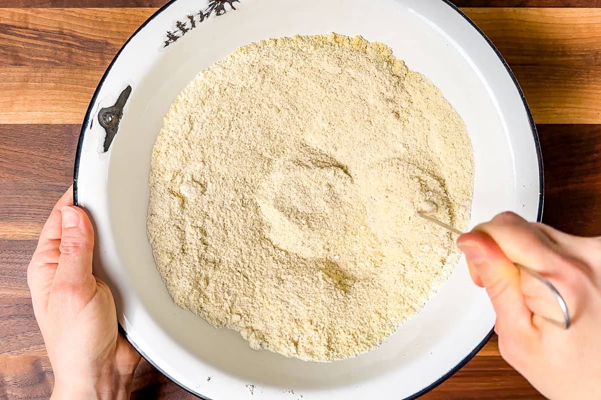 Stirring together the almond flour and tapioca starch in a large white bowl.