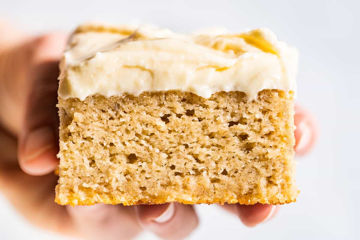 Close macro shot of a piece of gluten free banana cake topped with cream cheese frosting.