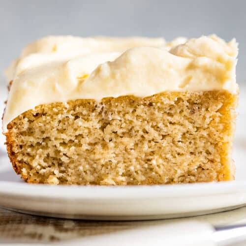 A slice of gluten free banana cake on a white plate with a blue background.